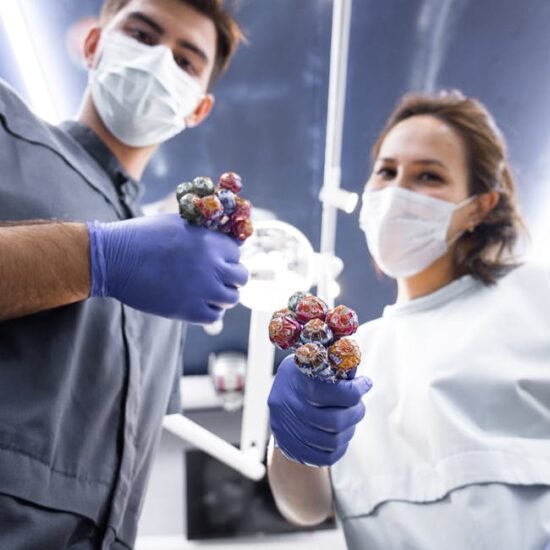 Two masked individuals with gloves offer bunches of lollipops, reflecting new normal practices.
