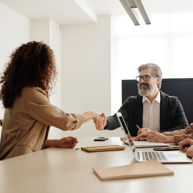 Colleagues in an office celebrating a successful negotiation with a handshake.